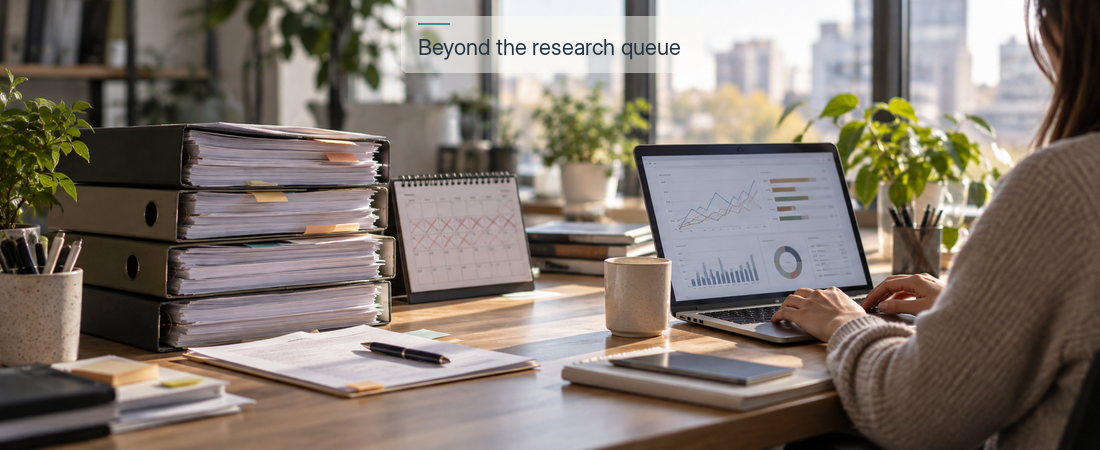 Stack of printed research reports beside a laptop showing live consumer insights dashboards